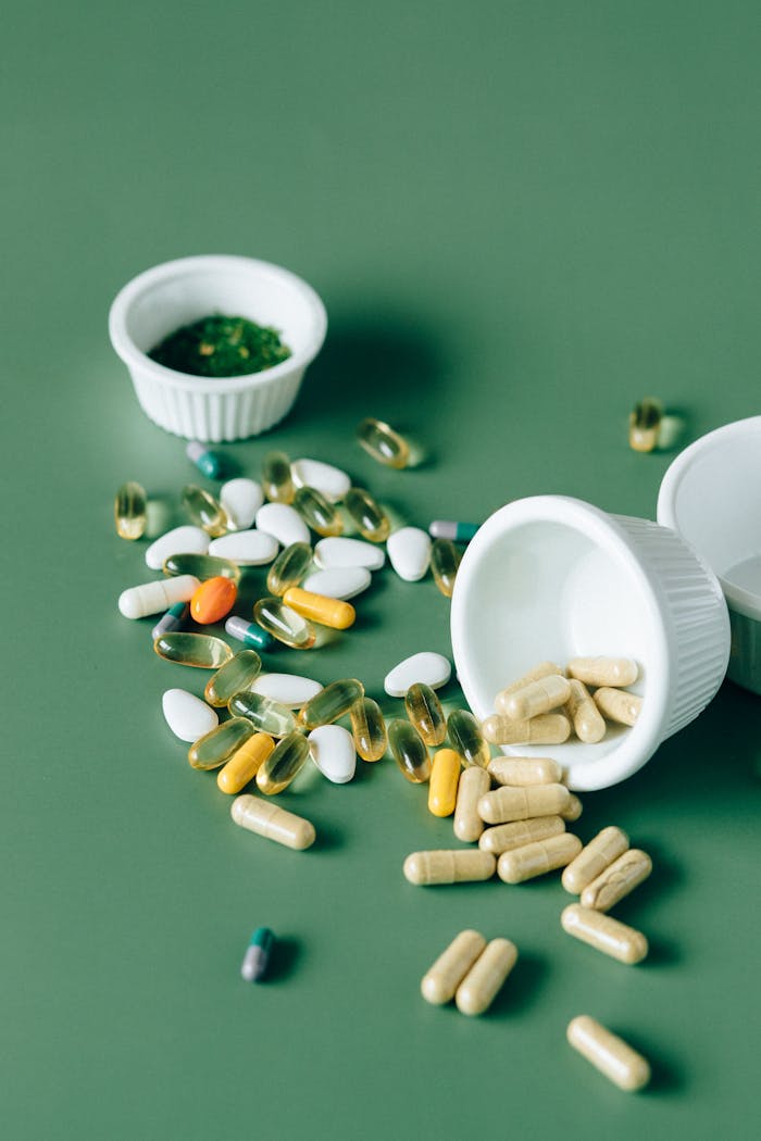 Variety of supplements and pills scattered on a green background, showcasing modern medicine concepts.